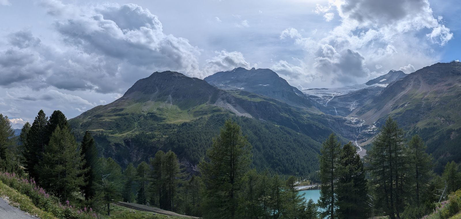 A green Alpine valley with snow-capped peaks, a glacier and a turquoise lake