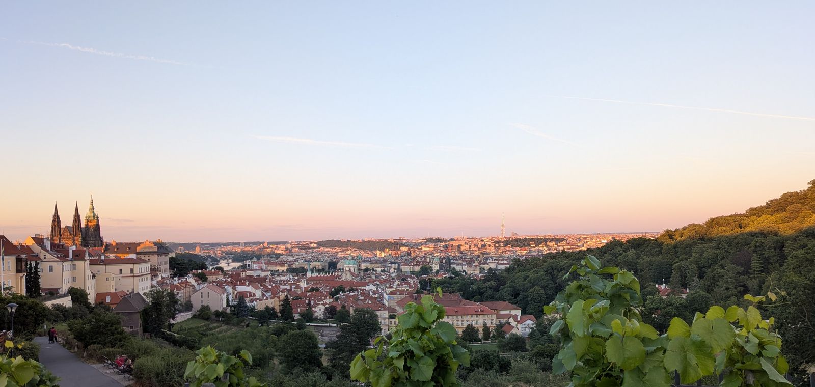 Prague Castle and the red rooftops of the city under a pink and orange dusk sky